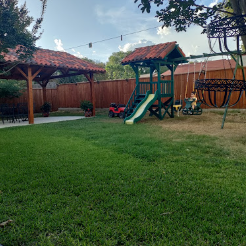 Spacious outdoor area with covered pergola and playground equipment